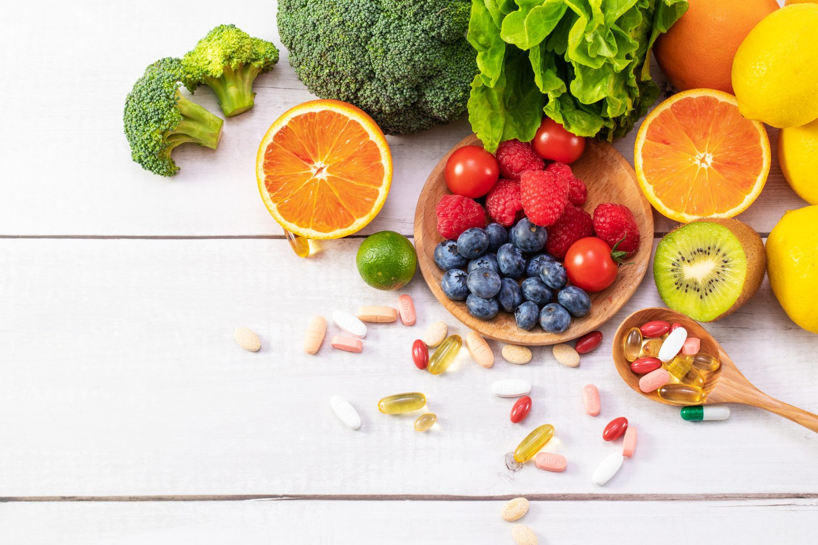 A top view of fresh fruits and vegetables with different medicine on a wooden spoon